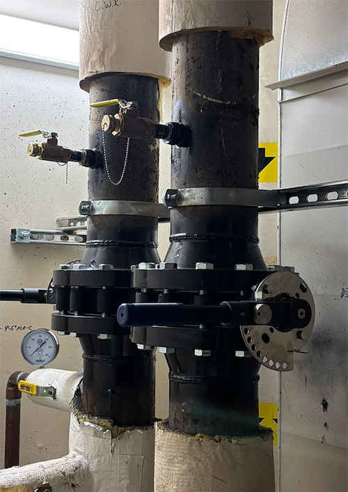 Commercial plumbing piping with large shutoff valves and pressure gauge.