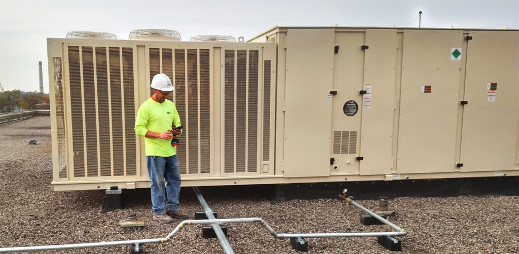 HVAC technician inspecting a large rooftop mechanical unit.