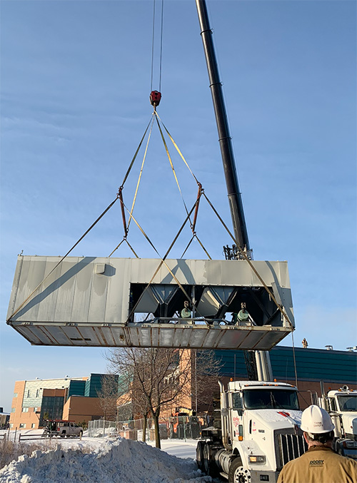 Rooftop HVAC unit being lifted by crane for commercial mechanical installation.